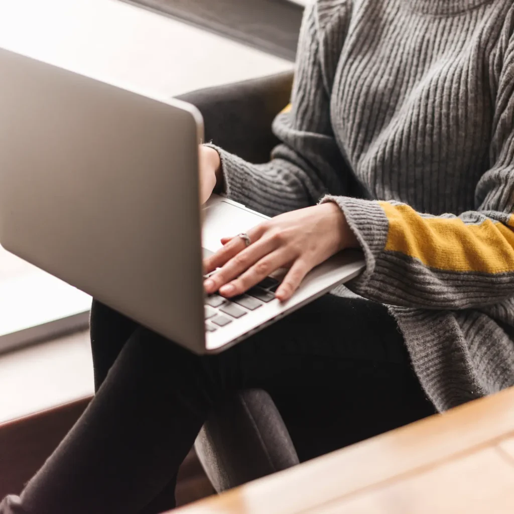 Mujer trabajando en un ordenador portátil en una cafetería, ideal para emprendedores que buscan mejorar su posicionamiento SEO.
