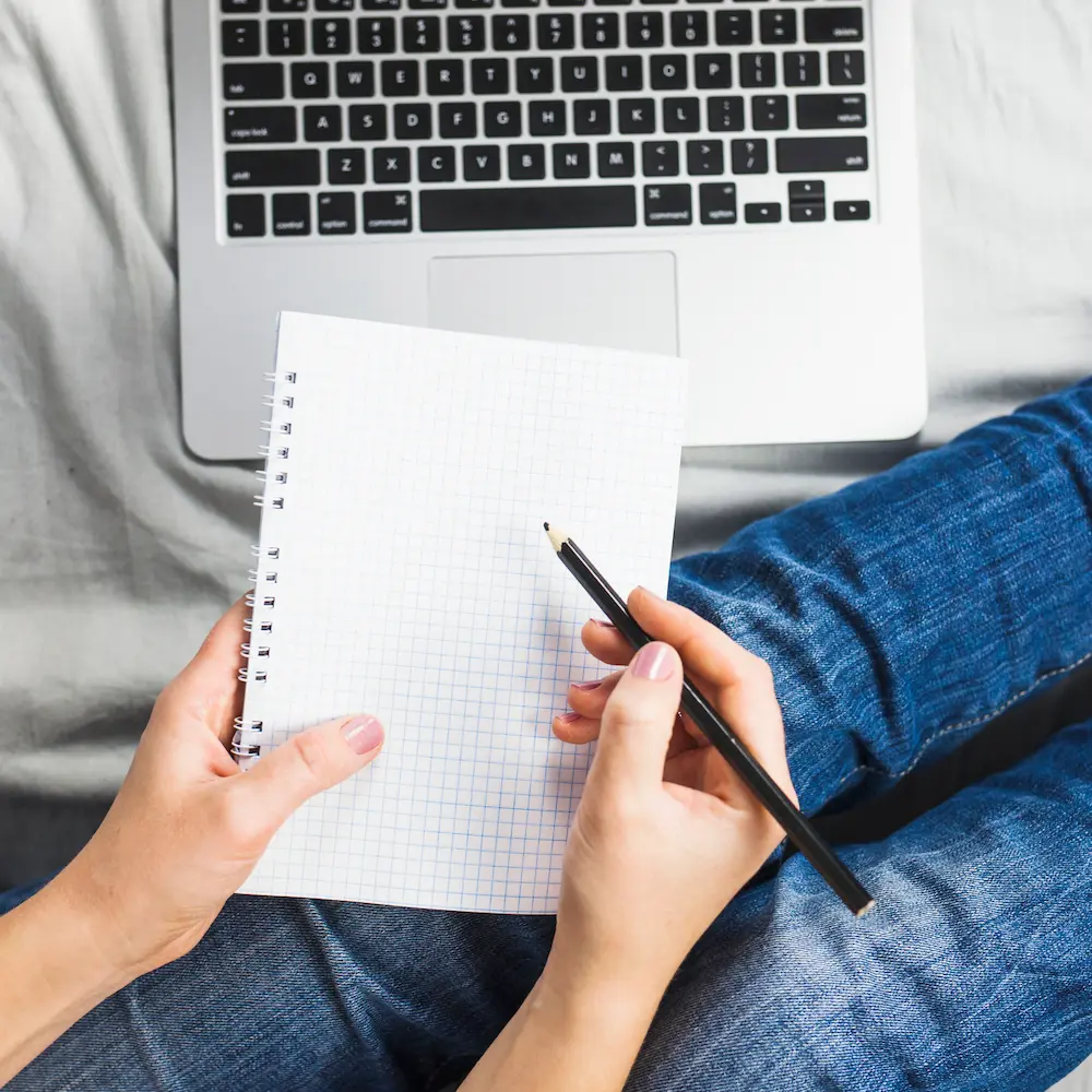 Emprendedora trabajando desde casa en su laptop con un cuaderno, ilustrando el servicio de desarrollo web WordPress dirigido a profesionales y negocios locales